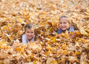 Çocuk yalan ve sonbahar Şehir Parkı içinde düşen yapraklar üzerinde oyun.