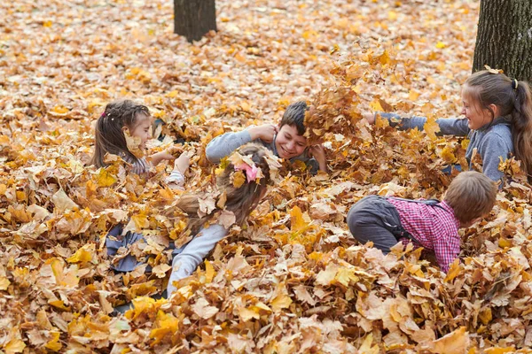 Los Niños Están Tumbados Jugando Con Hojas Caídas Parque Otoño — Foto de Stock