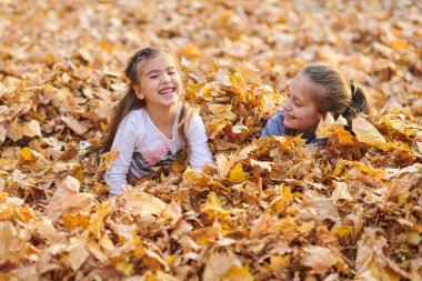 Çocuk yalan ve sonbahar Şehir Parkı içinde düşen yapraklar üzerinde oyun.