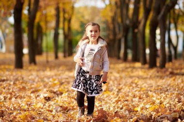 Kız çocuk sonbahar şehir park vardır. Parlak sarı ağaçlar.