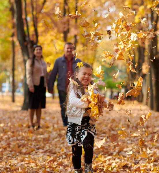 幸福的家庭是在秋天的城市公园 孩子和父母带着树叶跑 他们摆姿势 玩耍和乐趣 明亮的黄色树 — 图库照片