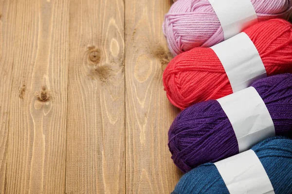 colorful wool threads for knitting on wooden background