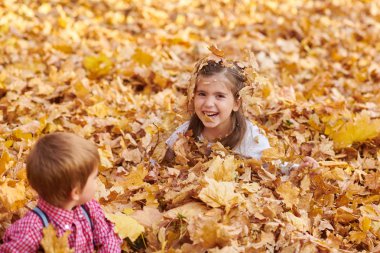 Çocuk yalan ve sonbahar Şehir Parkı içinde düşen yapraklar üzerinde oyun.