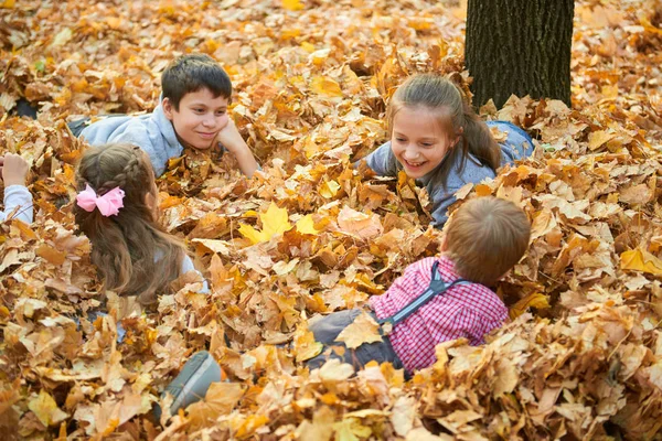 Děti Jsou Lhaní Hraje Spadané Listí Podzimním Parku — Stock fotografie