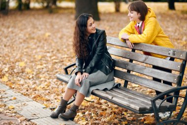 İki kız sonbahar şehir parkında bulunmaktadır. Bankta oturup konuşmak.
