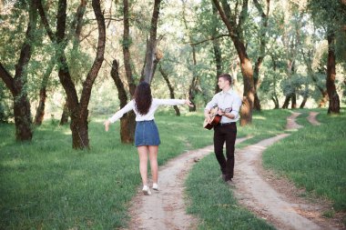 ormanda yürüyüş ve iskambil gitar, yaz doğa, parlak güneş ışığı genç çift, gölgeler ve yeşil yaprakları, romantik duygular