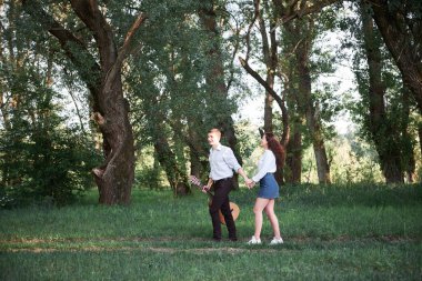 ormanda yürüyüş ve iskambil gitar, yaz doğa, parlak güneş ışığı genç çift, gölgeler ve yeşil yaprakları, romantik duygular