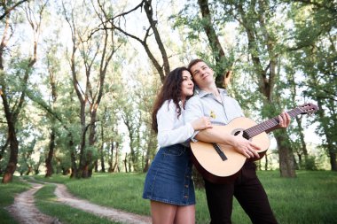 ormanda yürüyüş ve iskambil gitar, yaz doğa, parlak güneş ışığı genç çift, gölgeler ve yeşil yaprakları, romantik duygular