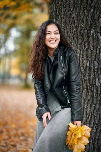 Kadın sarı yaprakları ile stand büyük ağaç sonbahar Şehir Parkı yakınındaki.