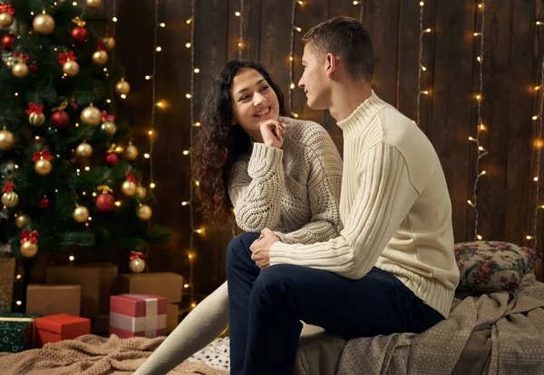 年轻夫妇在圣诞节灯光和装饰 穿着白色 冷杉树在黑暗的木背景 寒假概念 — 图库照片