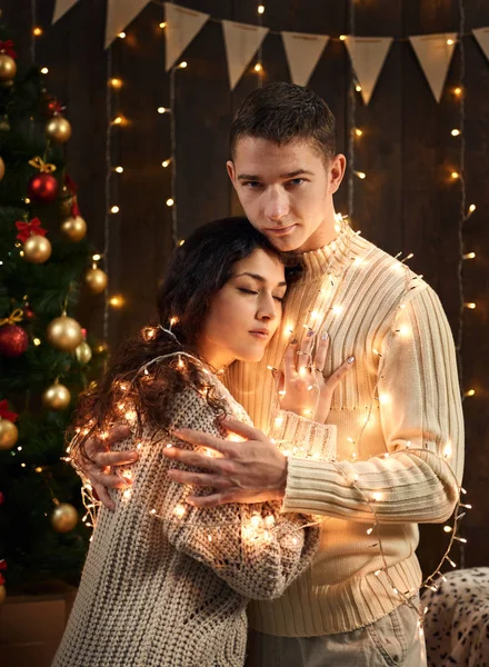 年轻夫妇是在圣诞节装饰和灯光 冷杉树在黑暗的木制背景下 新年假期的概念 — 图库照片