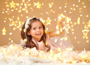 kız çocuk Noel ışıkları, sarı arka plan, pembe elbise ile poz