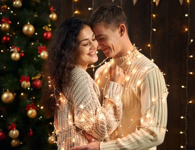 Genç bir çift olan Noel dekorasyonu ve ışıklar, köknar ağacı Yılbaşı tatil kavramı koyu ahşap arka plan üzerinde