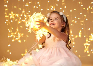 kız çocuk Noel ışıkları, sarı arka plan, pembe elbise ile poz