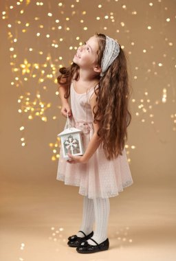 kız çocuk Noel ışıkları, sarı arka plan, pembe elbiseli fenerle poz
