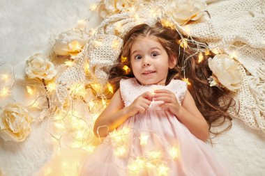 Kız Çocuk yalan Noel ışıkları ve çiçekler, yüz closeup ile