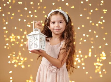 kız çocuk Noel ışıkları, sarı arka plan, pembe elbiseli fenerle poz