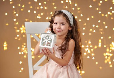 kız çocuk Noel ışıkları, sarı arka plan, pembe elbiseli fenerle poz