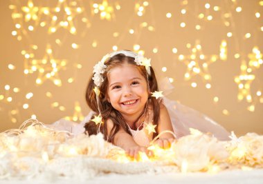 kız çocuk Noel ışıkları, sarı arka plan, pembe elbise ile oynuyor
