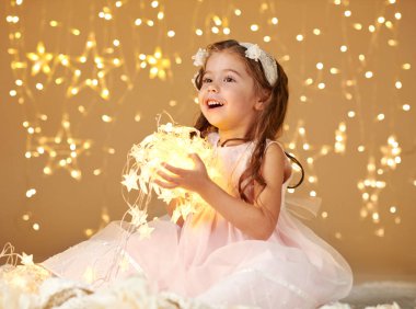 kız çocuk Noel ışıkları, sarı arka plan, pembe elbise ile poz