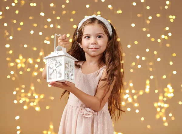 kız çocuk Noel ışıkları, sarı arka plan, pembe elbiseli fenerle poz