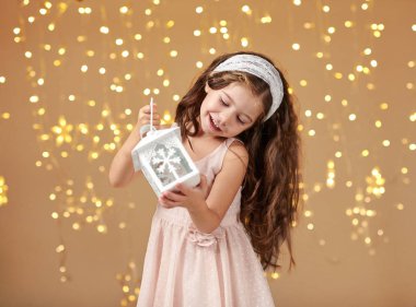 kız çocuk Noel ışıkları, sarı arka plan, pembe elbiseli fenerle poz