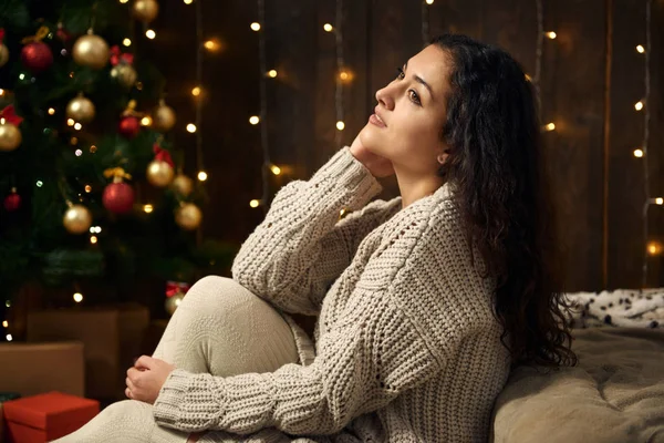 Mladá dívka je vánoční osvětlení a dekorace, oblečeni v bílém, jedle na tmavém pozadí dřevěná, Zimní dovolená concept — Stock fotografie