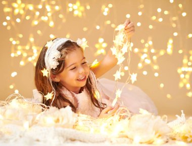 kız çocuk Noel ışıkları, sarı arka plan, pembe elbise ile poz