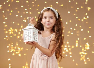 kız çocuk Noel ışıkları, sarı arka plan, pembe elbiseli fenerle poz
