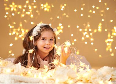 kız çocuk Noel ışıkları, sarı arka plan, pembe elbise ile poz