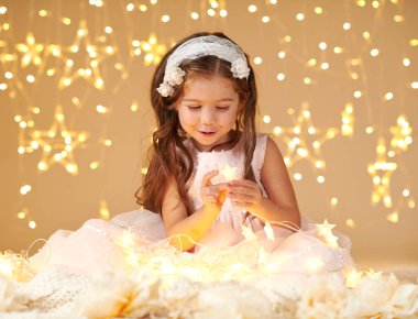 kız çocuk Noel ışıkları, sarı arka plan, pembe elbise ile oynuyor