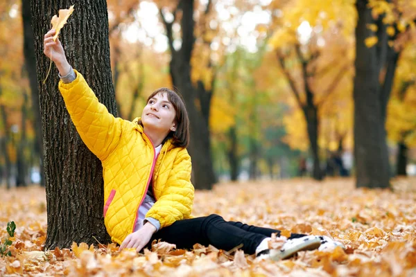 Teen Girl Siede Vicino All Albero Nel Parco Autunnale Gioca — Foto Stock