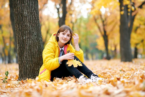 Dospívající Dívka Sedí Stromu Podzimním Parku Hraje Velkými Javorový List — Stock fotografie