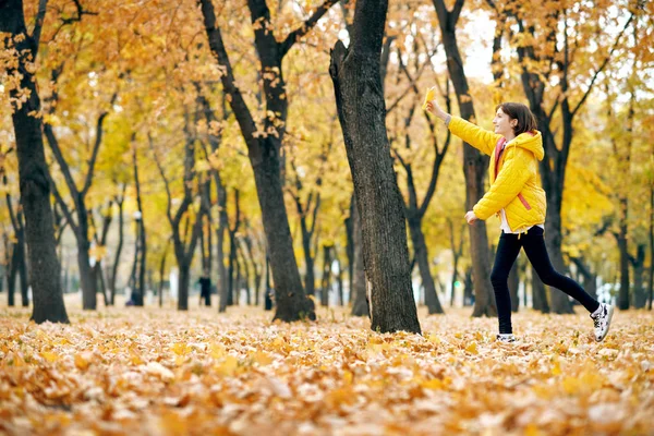 幸せな十代の少女は 大きなカエデの葉で秋の公園で実行されます 明るい黄色の葉や木 — ストック写真