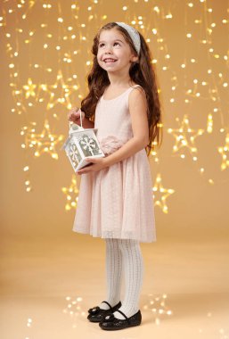 kız çocuk Noel ışıkları, sarı arka plan, pembe elbiseli fenerle poz