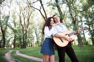 ormanda yürüyüş ve iskambil gitar, yaz doğa, parlak güneş ışığı genç çift, gölgeler ve yeşil yaprakları, romantik duygular