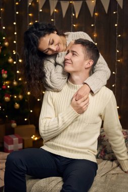 Noel ışıkları ve dekorasyon, beyaz, koyu ahşap arka plan, kış tatil kavramı üzerinde köknar ağacı giymiş genç çift mevcuttur