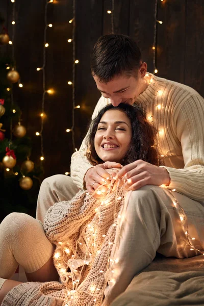 年轻夫妇是在圣诞节装饰和灯光 冷杉树在黑暗的木制背景下 新年假期的概念 — 图库照片