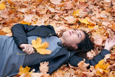 Güzel kadın düşen yapraklar üzerinde sonbahar parkta yatıyor. Sonbahar sezonu, güzel manzara.
