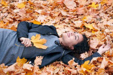 Güzel kadın düşen yapraklar üzerinde sonbahar parkta yatıyor. Sonbahar sezonu, güzel manzara.