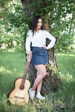 ormanda yürüyüş ve iskambil gitar, yaz doğa, parlak güneş ışığı, gölgeler ve yeşil yaprakları, romantik duygular genç kadın