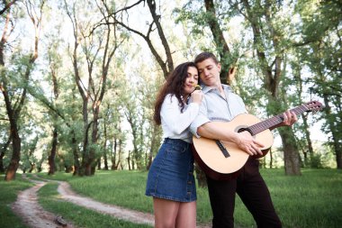 ormanda yürüyüş ve iskambil gitar, yaz doğa, parlak güneş ışığı genç çift, gölgeler ve yeşil yaprakları, romantik duygular