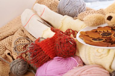 Bir pencere pervazına yün iplikler ile sıcak çorap alt bacaklar yanıyor.