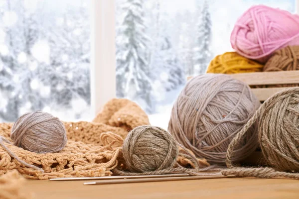 Woolen yarn and fabric on the window sill. Beautiful view outside the window - winter scenery and snow.