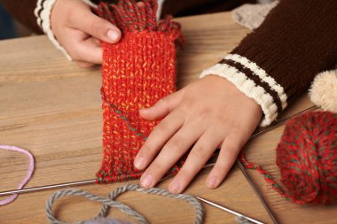 Çocuk çocuk örgü örmeyi öğreniyor. Renkli yün iplikler ahşap masa vardır. El portre.