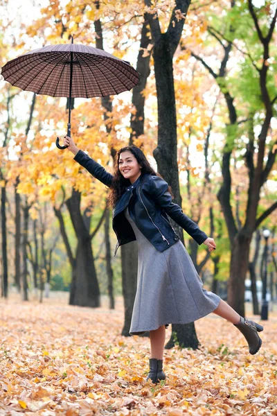 秋天公园里摆着伞的女人 明亮的黄色树叶和树木 她模仿风 — 图库照片