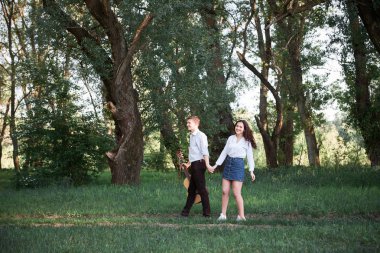 ormanda yürüyüş ve iskambil gitar, yaz doğa, parlak güneş ışığı genç çift, gölgeler ve yeşil yaprakları, romantik duygular