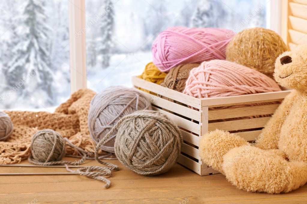 Woolen yarn and fabric on the window sill. Beautiful view outside the window - winter scenery and snow.