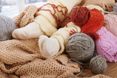 Bir pencere pervazına yün iplikler ile sıcak çorap alt bacaklar yanıyor.