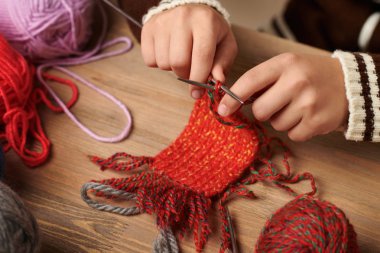 Çocuk çocuk örgü örmeyi öğreniyor. Renkli yün iplikler ahşap masa vardır. El portre.